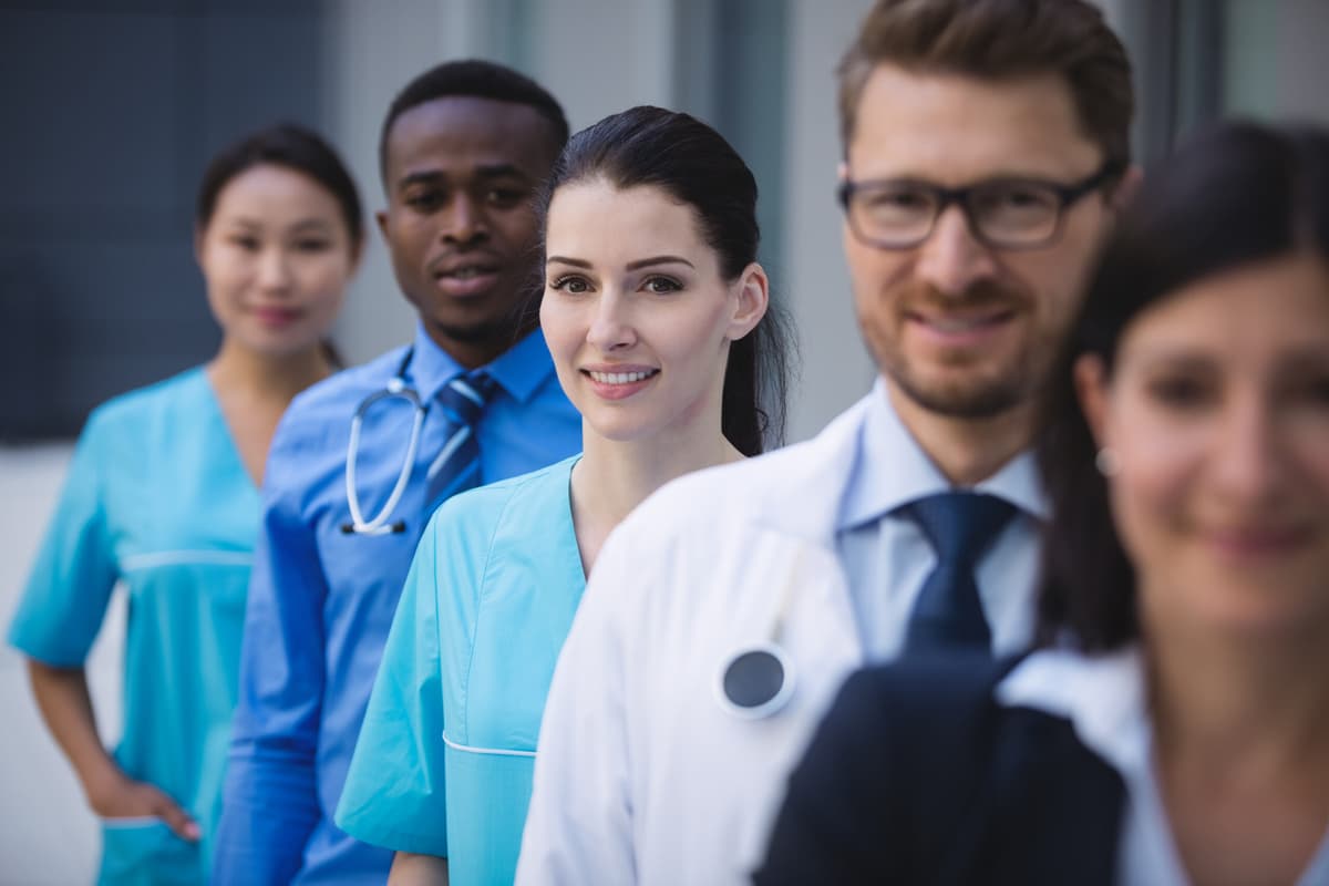 coronis health Portrait of smiling doctors standing in row at hospital premises