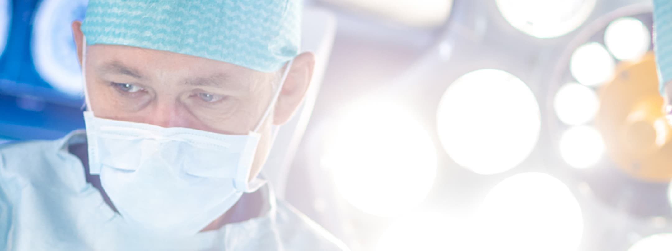 Anesthesiologist in scrubs monitoring patient vitals during surgery