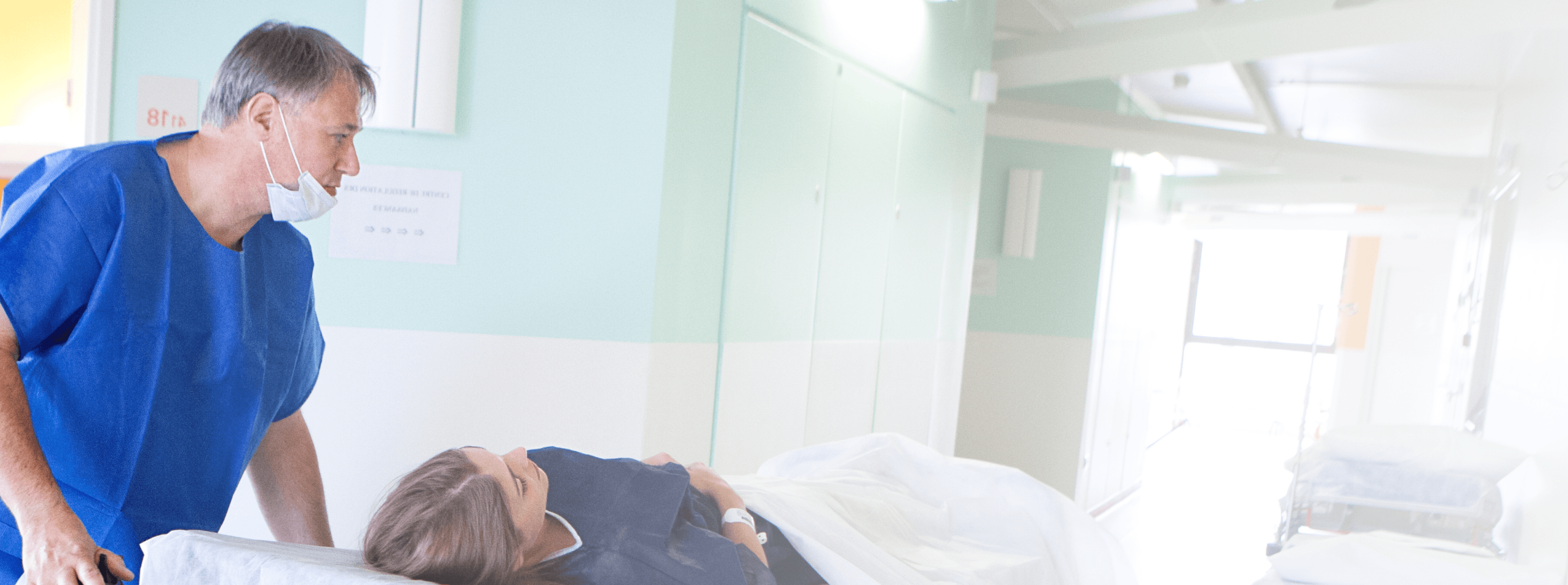 Photo of a medical professional transporting a patient on a hospital bed