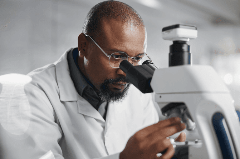 Healthcare, microscope and science with man in lab for medical or pharmaceutical research. Innovation, sample and study with African scientist at work for analysis, development or experiment results